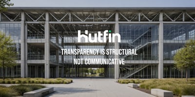 Modern glass office building with exposed structural framework and a central open walkway, emphasizing architectural transparency and symmetry.