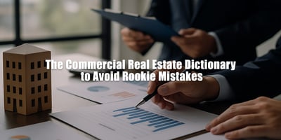 Two professionals in suits reviewing financial charts at a desk with a small wooden building model, while one points to a bar graph and the other holds a clipboard. Overlaid text reads: “The Commercial Real Estate Dictionary to Avoid Rookie Mistakes.”
