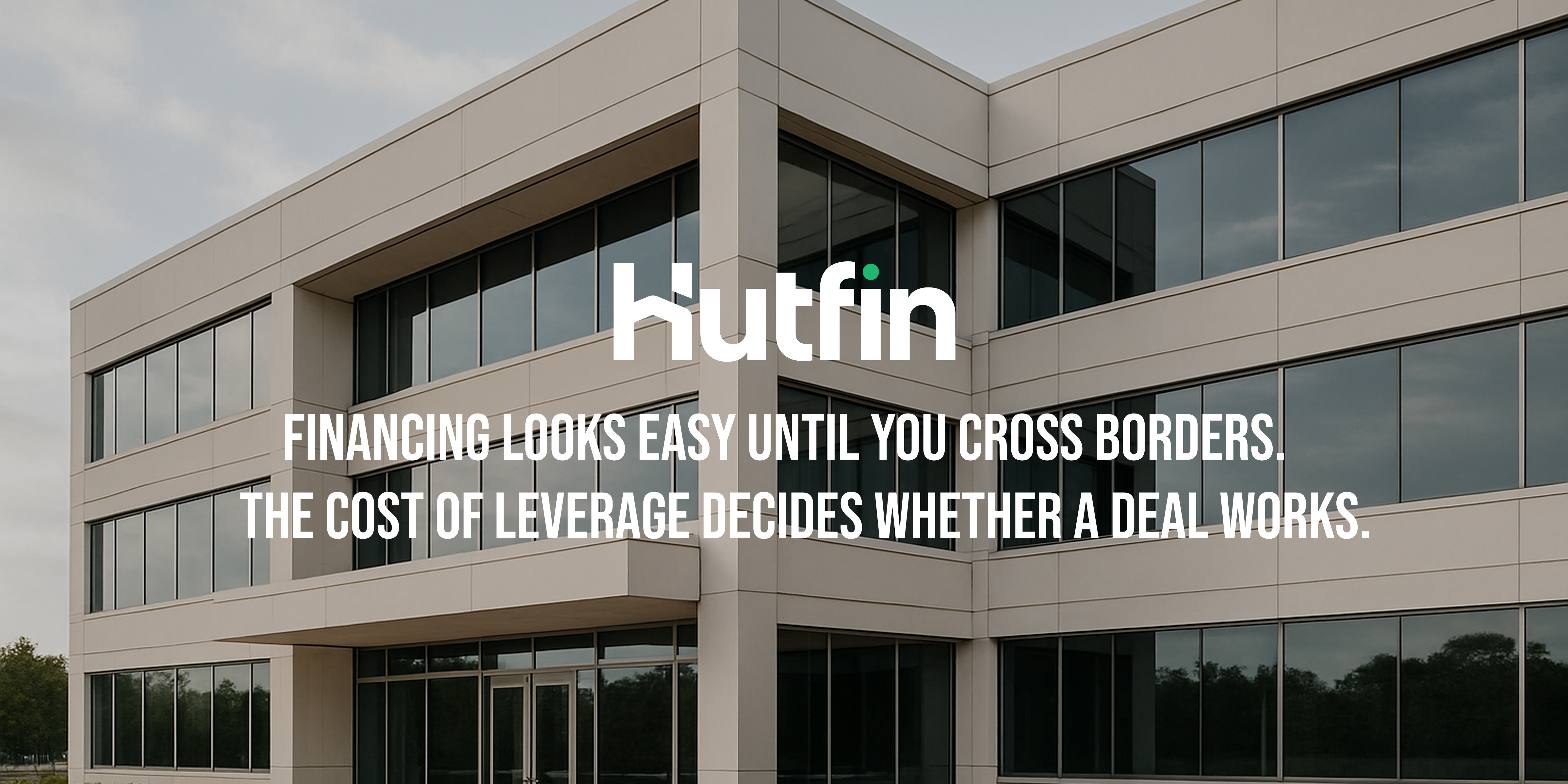 A modern mid-rise commercial office building with large reflective windows and clean architectural lines, photographed on an overcast day.